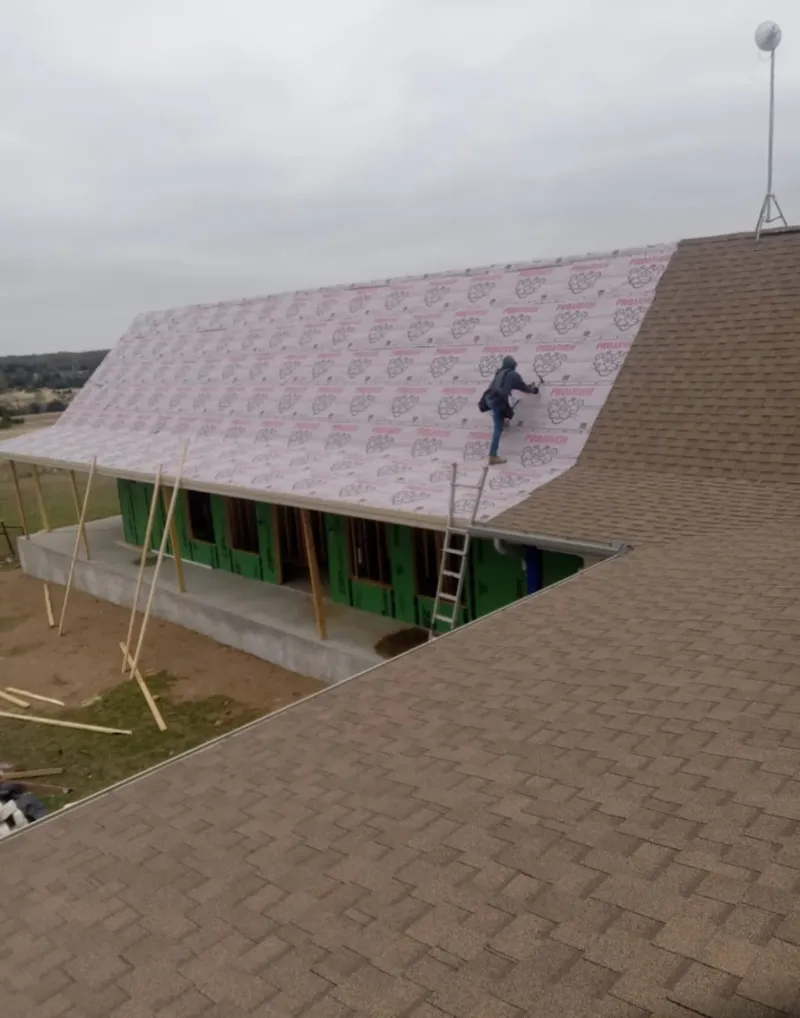 Worker preparing underlayment for a metal roof installation in Portage